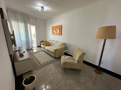 Sala de dois ambientes com muita iluminação natural, mesa de jantar e sofá.