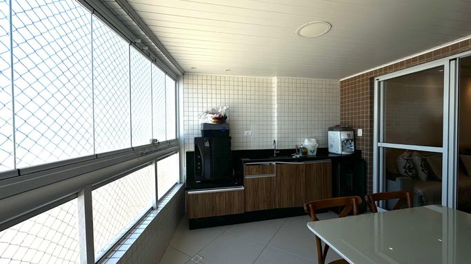 Sacada gourmet envidraçada com vista para o mar.