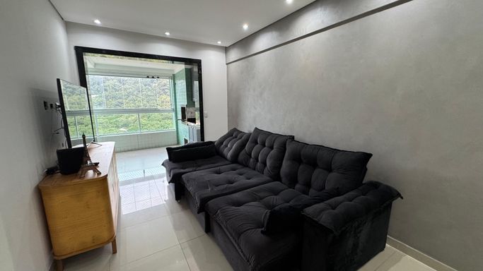 Sala com dois ambientes, equipada com mesa de jantar para seis lugares, sofá, parede espelhada e ar-condicionado.