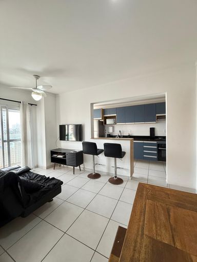 Sala de dois ambientes com mesa de jantar, sofá cama, acesso a sacada gourmet e ventilador de teto.