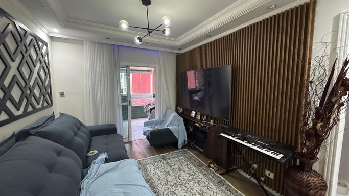 Sala de 2 ambientes com painel ripado, lustre pendente e ar-condicionado.