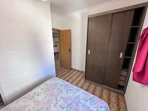 Dormitório muito bem iluminado com uma cama de casal e guarda-roupa.