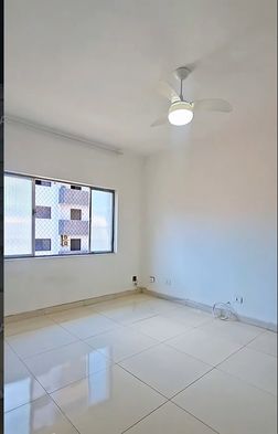 Sala bem iluminada com paredes brancas e ventilador de teto.