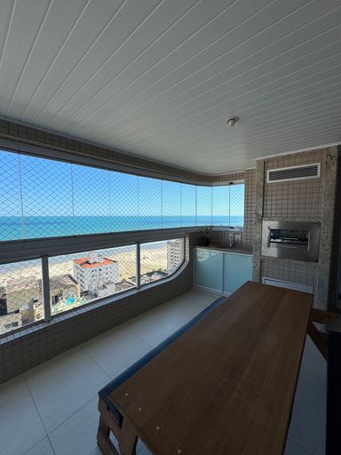 Sacada gourmet envidraçada com vista para o mar.