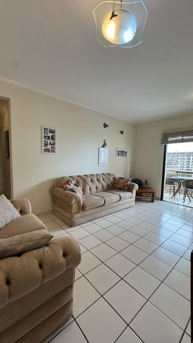 Sala ampla, com 2 sofás, mesa de jantar e acesso à sacada.