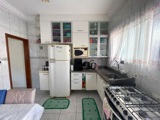 Cozinha americana com mesa para quatro pessoas, armários planejados e fogão.