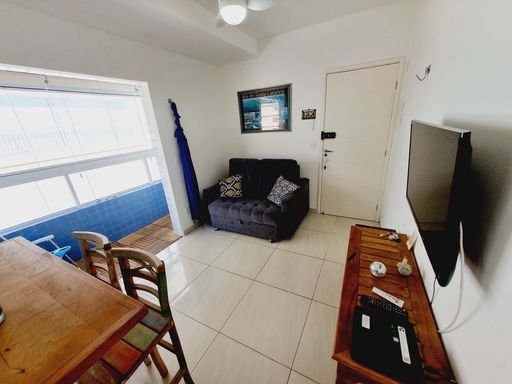 Sala bem iluminada com um sofá e sacada.