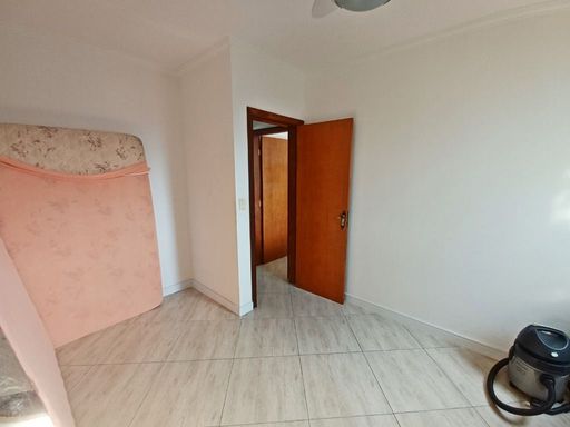 Dormitório com muita iluminação natural, com ar-condicionado de janela e ventilador de teto.