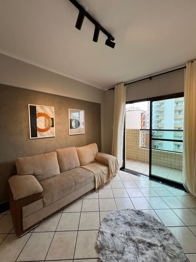 Sala ampla e bem iluminada com um sofá e painel de TV.