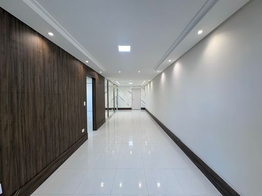 Sala ampla de 2 ambientes com teto rebaixado em gesso com iluminação em LED e parede espelhada.