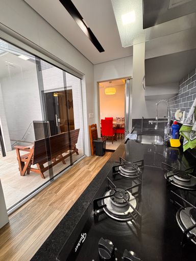 Cozinha integrada à piscina, completamente planejada, com fogão, coifa e geladeira.