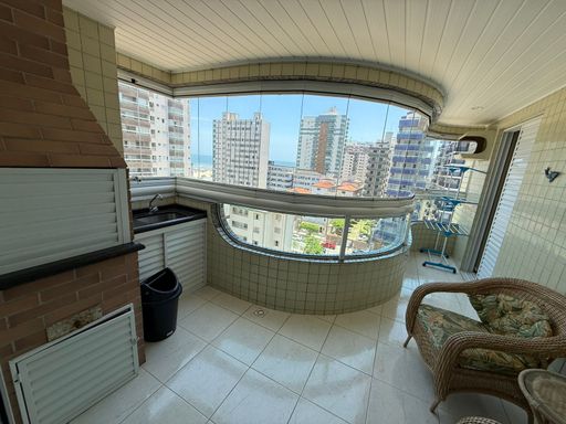 Sacada gourmet envidraçada com vista para o mar.