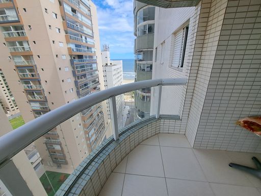 Sacada gourmet com churrasqueira a carvão e vista lateral para o mar.