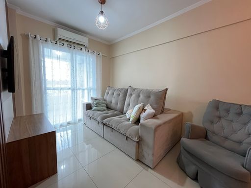 Sala de 2 ambientes com sofá de 2 lugares, painel de TV e TV.