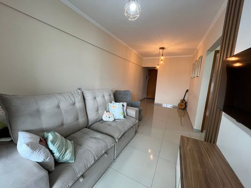 Sala de 2 ambientes com sofá de 2 lugares, painel de TV e TV.