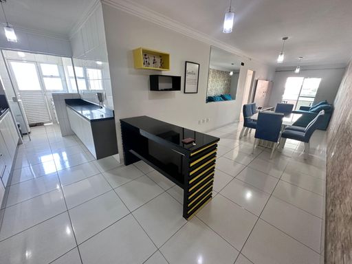 Sala de dois ambientes integrada à cozinha americana, que conta com armários planejados.