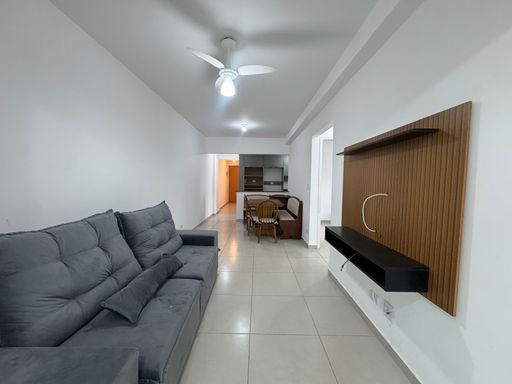 Sala ampla de 2 ambientes com mesa de jantar, sofá e painel de TV e ventilador de teto.