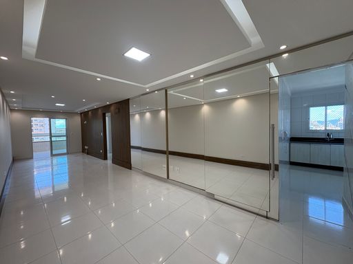 Sala ampla de 2 ambientes com teto rebaixado em gesso com iluminação em LED e parede espelhada.