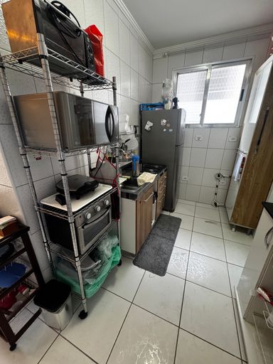 Cozinha com uma geladeira, pia, fogão e micro-ondas.