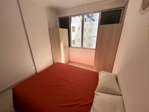 Sala living bem iluminada com uma cama de casal.