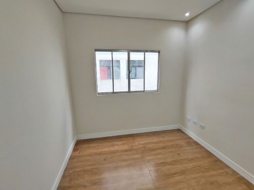 Sala com uma janela grande e piso laminado.