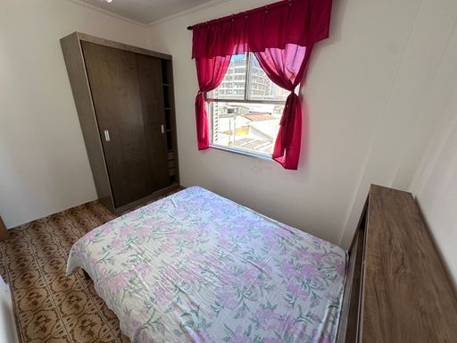 Dormitório muito bem iluminado com uma cama de casal e guarda-roupa.