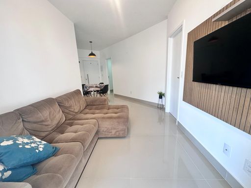 Sala ampla de 2 ambientes com um sofá e acesso a sacada gourmet.