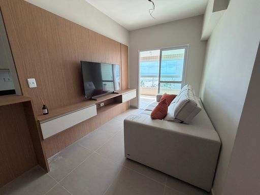 Sala de dois ambientes com um sofá e painel de TV.