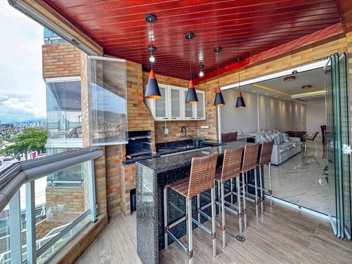 Sacada gourmet envidraçada com vista para o mar.