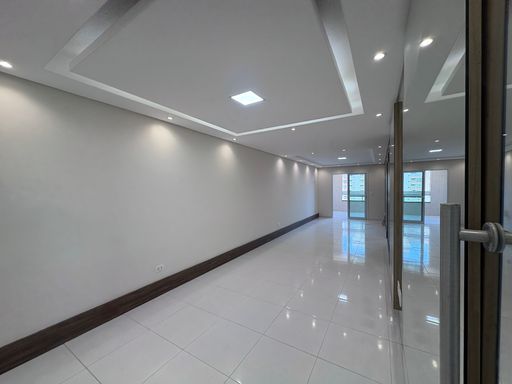 Sala ampla de 2 ambientes com teto rebaixado em gesso com iluminação em LED e parede espelhada.