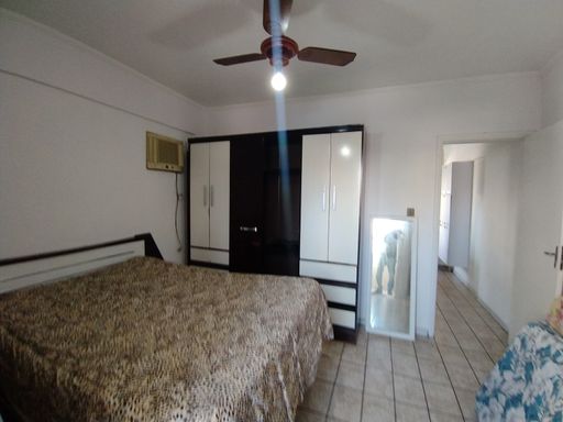 Dormitório amplo e bem iluminado com uma sacada privativa e ventilador de teto.