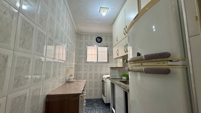 Cozinha com armários, pia, gabinete, fogão e geladeira.