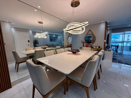 Sala ampla de 2 ambientes com uma parede espelhada e  mesa de jantar.