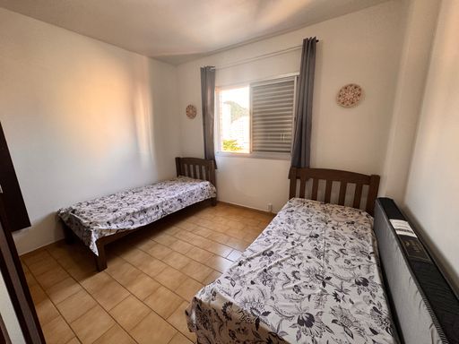 Dormitório muito bem iluminado com duas camas de solteiro e uma guarda-roupa.