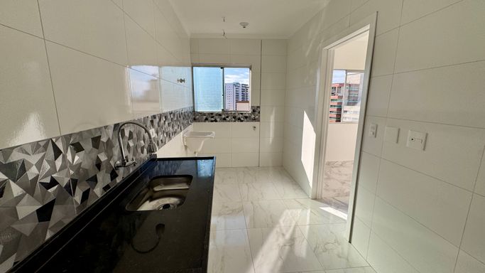 Cozinha bem iluminada com uma pia e tanque branco.