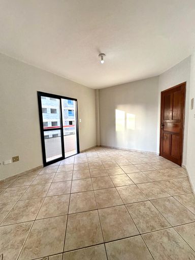 Sala bem iluminada com uma sacada privativa.