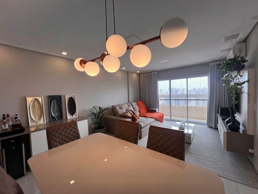 Sala ampla de 02 ambientes com sofá, mesa de jantar para seis pessoas, ar-condicionado e acesso a sacada gourmet.