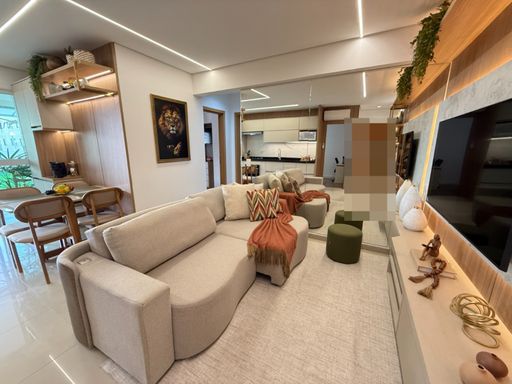 Sala com painel de TV com iluminação em LED, parede espelhada, sofá e ar-condicionado.