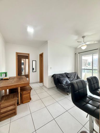 Sala de dois ambientes com mesa de jantar, sofá cama, acesso a sacada gourmet e ventilador de teto.