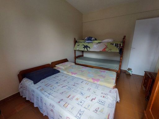 Dormitório espaçoso com duas camas de solteira, um beliche e guarda-roupa.