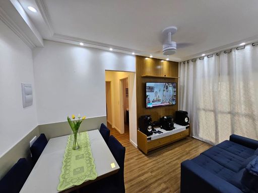 Sala de 2 ambientes com um sofá, painel de TV e mesa de jantar.