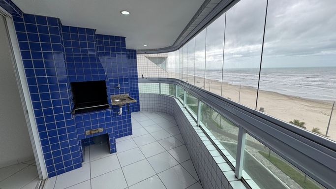 Sacada gourmet envidraçada com vista para o mar.