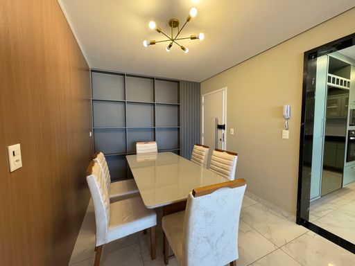 Sala de dois ambientes com nichos na parede, ar-condicionado, sofá e acesso à sacada gourmet.