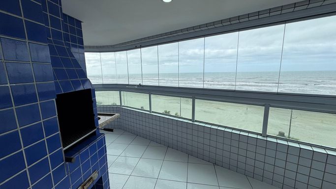 Sacada gourmet envidraçada com vista para o mar.