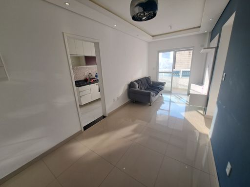 Sala de dois ambientes com muita iluminação natural, uma parede azul e outra branca, com sofá e painel de TV.