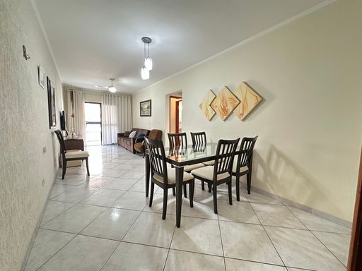 Sala ampla com dois ambientes, excelente iluminação natural, equipada com mesa de jantar para seis pessoas, sofá, rack e TV.