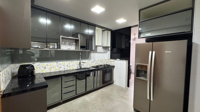 Cozinha americana totalmente planejada com geladeira de duas portas.