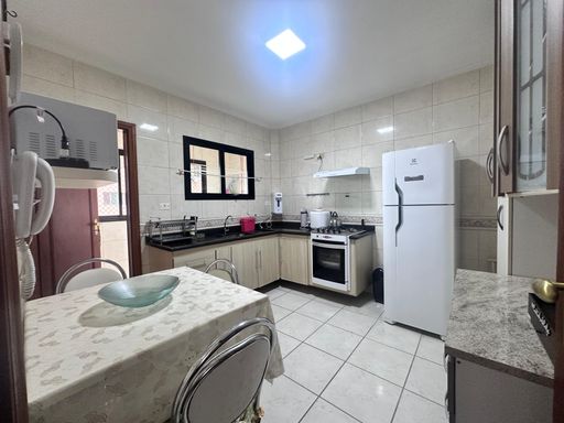 Cozinha espaçosa com uma pia, geladeira, fogão e armários brancos.