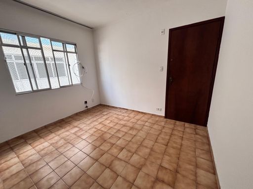 Sala bem iluminada com uma janela grande e parede cinza.