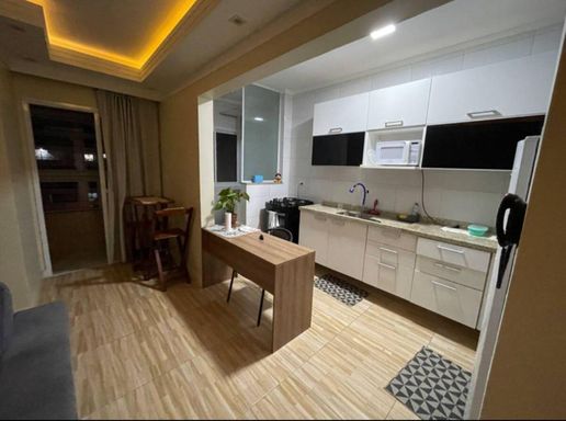 Sala espaçosa, com teto rebaixado em gesso, iluminação em LED e ventilador de teto e cozinha americana com planejados.